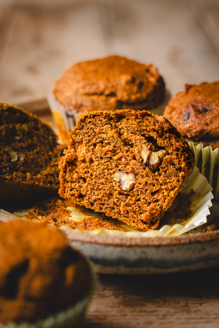 vegan pumpkin muffins on a plate, one muffin cut in half