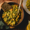 bowl of vegan chickpea spinach curry with bread
