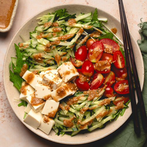 sesame mizuna salad on plate, dressing on the side