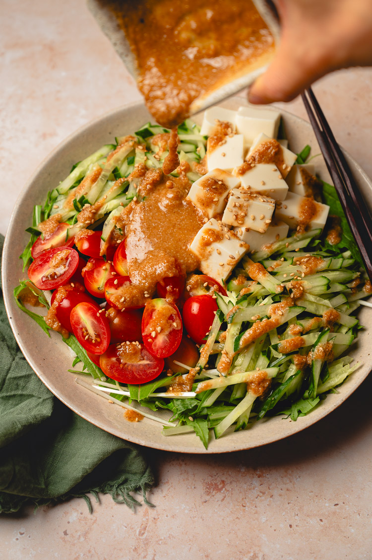 sesame dressing being drizzled on mizuna salad