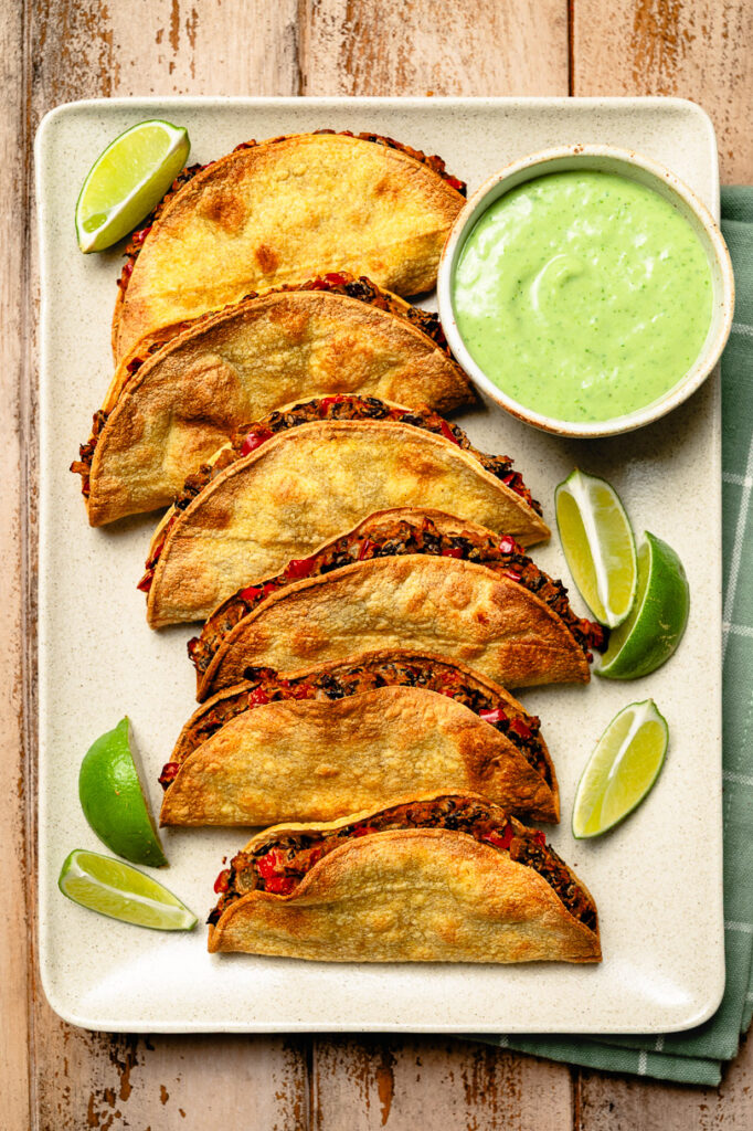 platter of crispy black bean tacos with cilantro lime sauce